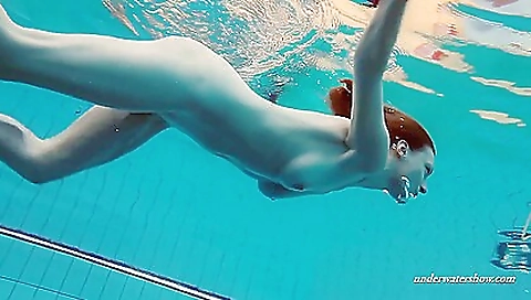 Sexy redhead in a pink lingerie is swimming in a pool